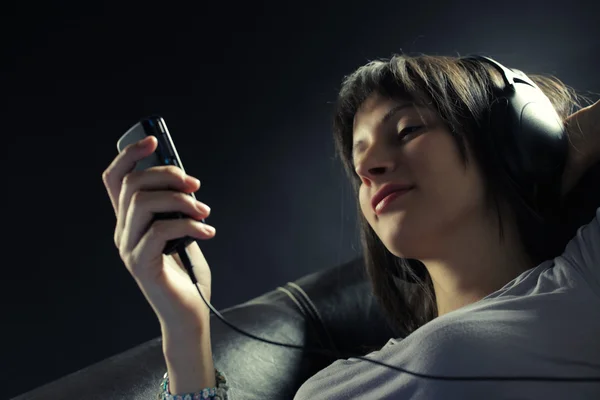 Avslappnad ung kvinna liggande på soffan när du lyssnar musik i headp — Stockfoto