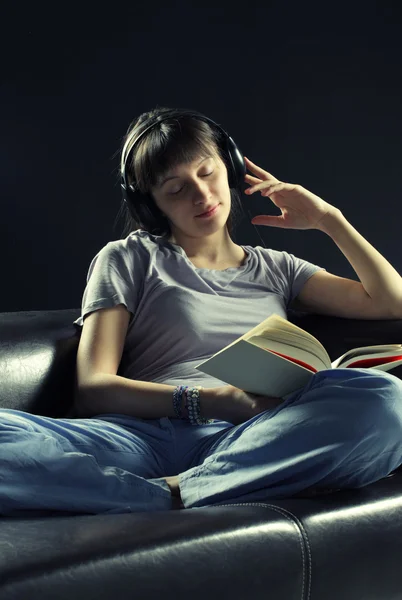 Relaxed young woman listening music and reading a book — Stock Photo, Image