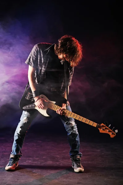 Rock bassist plays his bass on a dark background — Stock Photo, Image