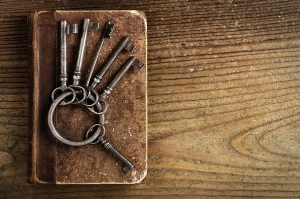 Старые ключи на старой книге, старинный деревянный фон — стоковое фото
