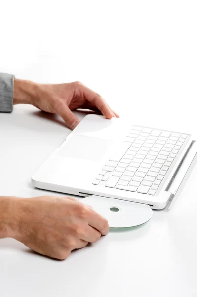Uomo d'affari inserendo un cd sul computer portatile bianco — Foto Stock