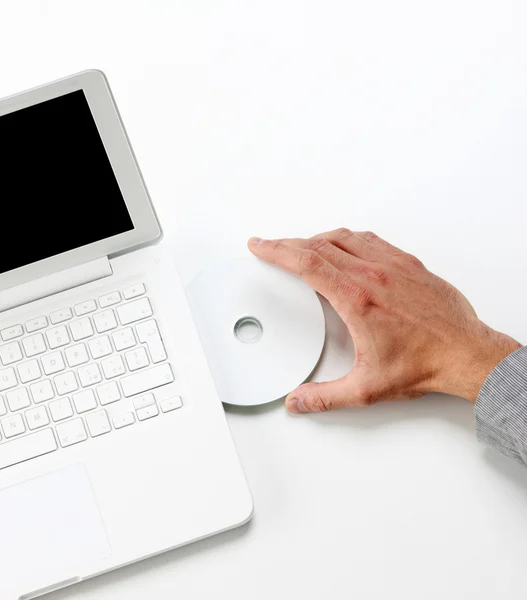 Επιχειρηματίας εισαγωγή ενός cd στο λευκό lap-top - κάτοψη — Φωτογραφία Αρχείου