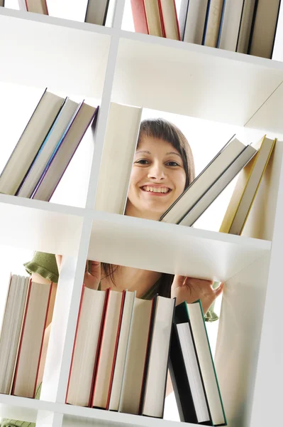 Ung kvinna söker en bok på biblioteket — Stockfoto