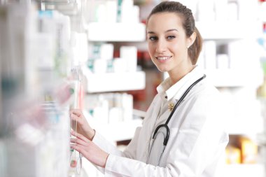 Young female pharmacist reaching for medicine from counter