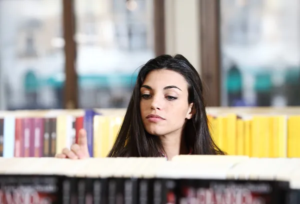 Mujer joven y bonita buscando un libro en una librería — Foto de Stock
