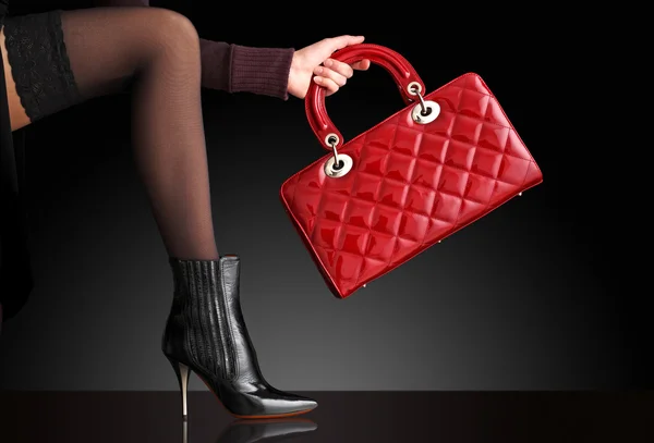 La mujer a la moda con la bolsa roja, solamente las piernas — Foto de Stock