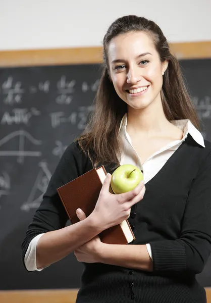 Retrato de un estudiante sonriente con manzana frente a una blackboa — Foto de Stock