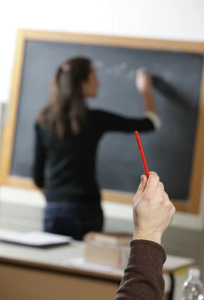 Uczeń zadaje pytanie do nauczyciela, który pisze na blac — Zdjęcie stockowe