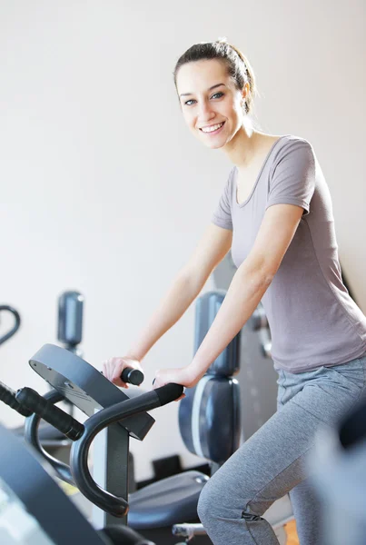 Portrait of young woman riding an exercise bike — Stock Photo, Image