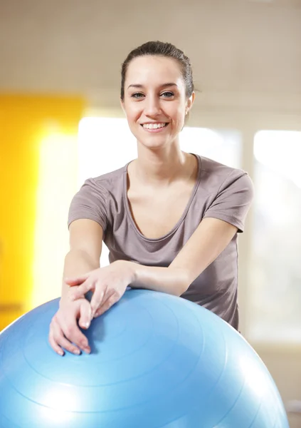 Vonzó fiatal nő támaszkodva az edzőteremben gyakorlat labda — Stock Fotó