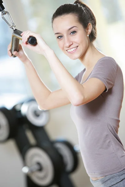 Uśmiechnięta młoda kobieta robi na maszynie wagi w klubie zdrowia — Zdjęcie stockowe