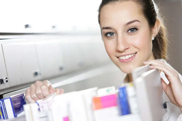 Young female pharmacist reaching for medicine — Stock Photo, Image