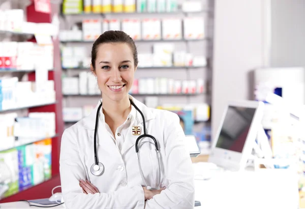 Bij apotheek. een lachende jonge vrouw apotheker met stethoscoop — Stockfoto