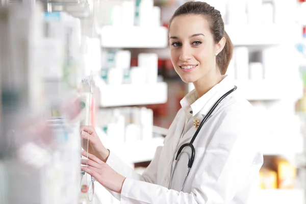 Giovane farmacista femminile che cerca la medicina dal bancone — Foto Stock
