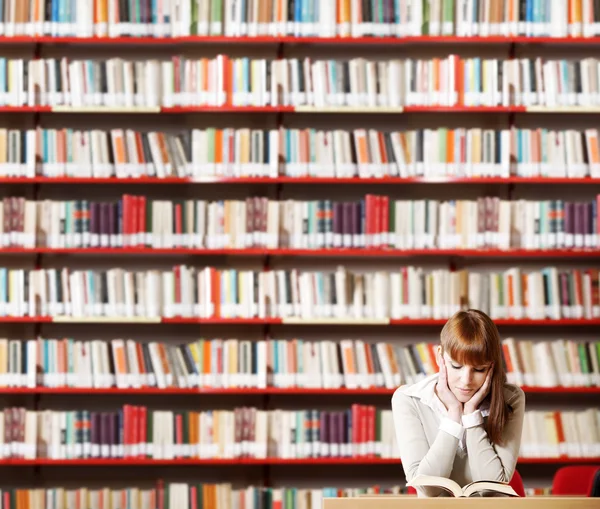 Junge Studentin in einer Bibliothek Stockbild