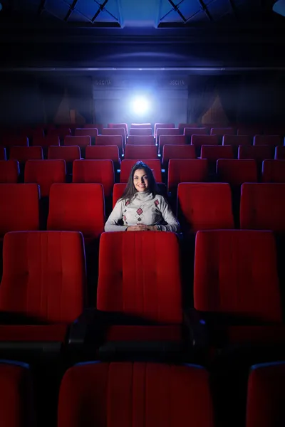 Beautiful young woman alone sitting in a empty movie theater — Stock Photo, Image
