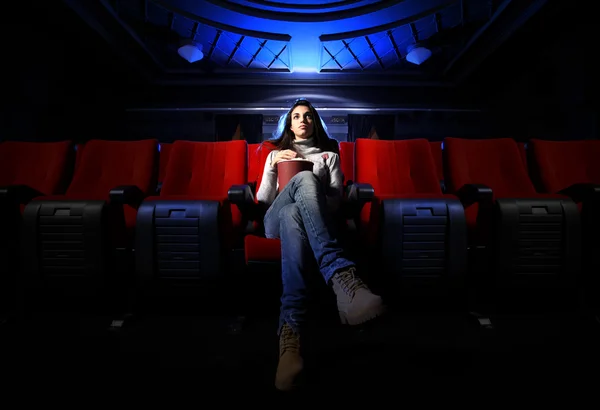 Eine hübsche junge Frau sitzt allein in einem leeren Theater, — Stockfoto