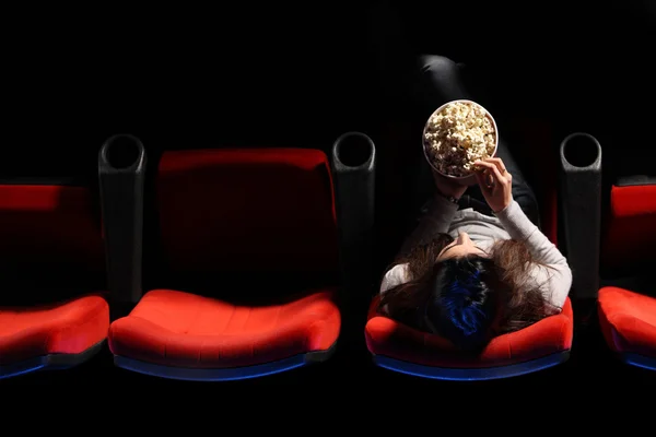 Eine hübsche junge Frau sitzt in einer Reihe roter Stühle in einem Theater — Stockfoto