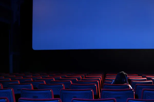 The end: youn woman alone sitting in a empty movie theater, rear — стоковое фото