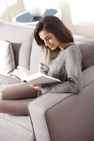 Портрет молодой женщины, лежащей на диване с книгой — стоковое фото