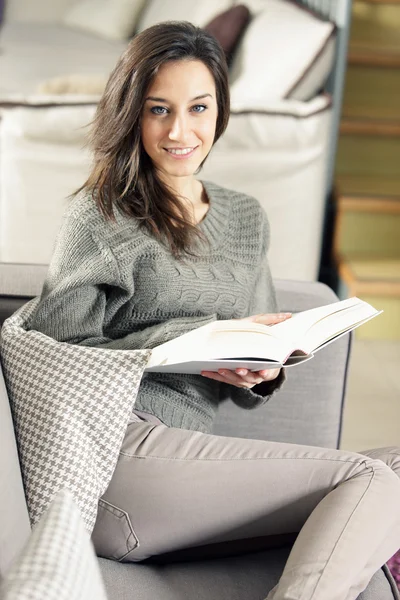 Retrato de una joven feliz acostada en un sofá con libro —  Fotos de Stock