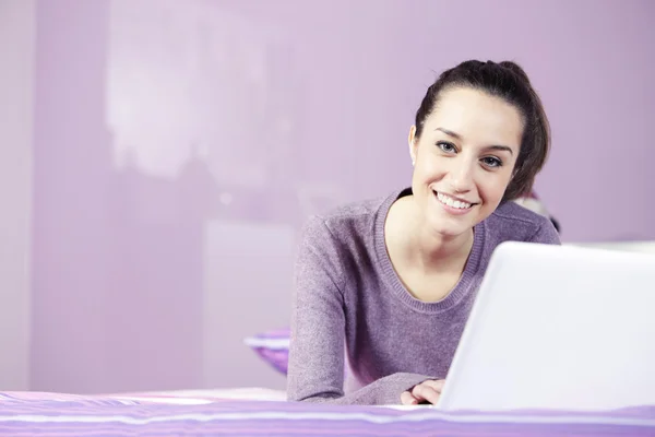Genç kadın yatakta dizüstü bilgisayar kullanırken dinlendirici bir portresi: c — Stok fotoğraf