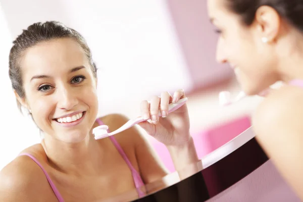 stock image Young woman in bathroom cleaning her teeth