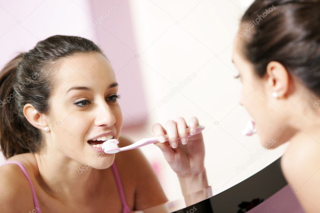 Young woman in bathroom cleaning her teeth