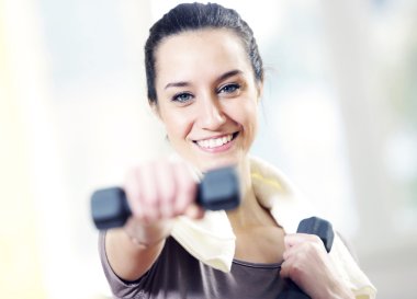 Dumbbell in hand of working out young smiling female clipart