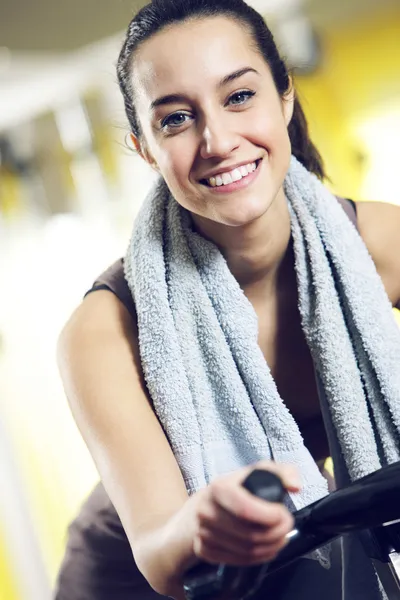 A young woman riding an exercise bike — Stock Photo, Image