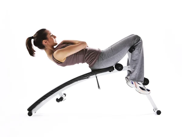 Mulher usando máquinas de fitness, fundo branco — Fotografia de Stock