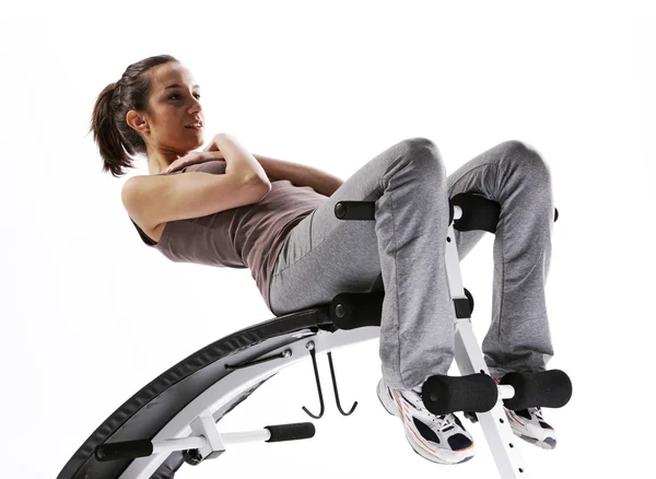 Woman using fitness machinery, white background — Stock Photo, Image