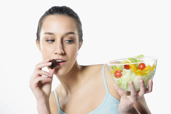 Концепция диеты: жесткий выбор между овощами и шоколадом — стоковое фото