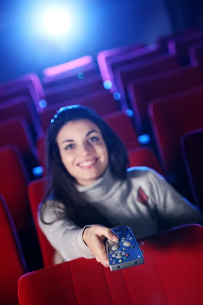 Жінка тримає телевізор з пультом дистанційного керування в кінотеатрі. концепція — стокове фото