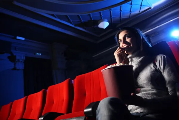 Une jolie jeune femme assise dans un théâtre vide, elle mange du popco — Photo