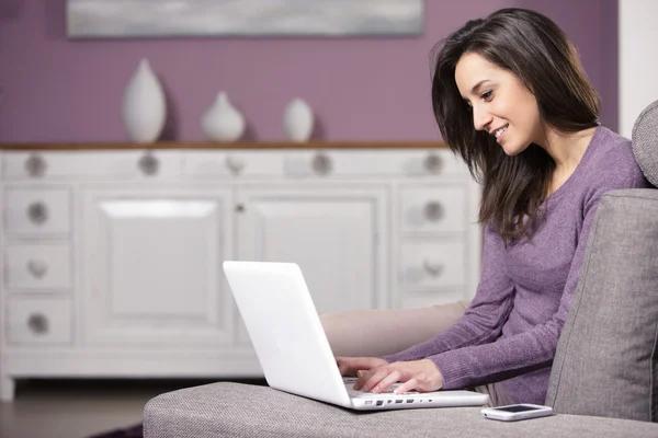 Portrait of young woman on the sofa using laptop — Stock Photo, Image