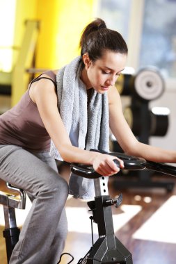 A young woman riding an exercise bike clipart