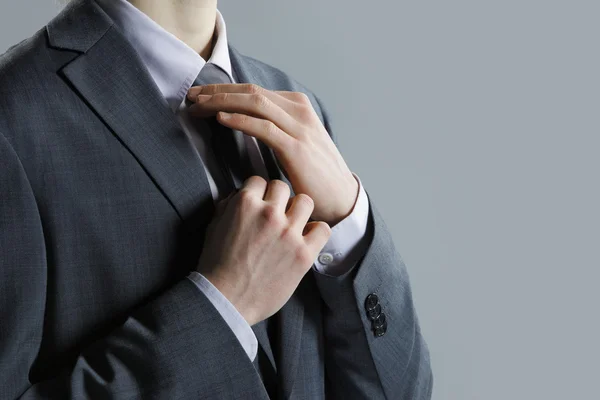 Ein Geschäftsmann im grauen Anzug überprüft seine Krawatte — Stockfoto
