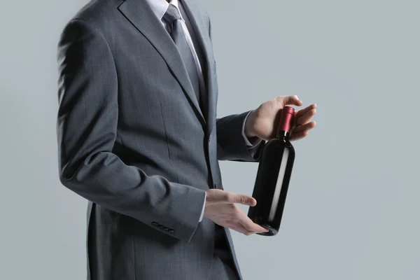 Elegancki mężczyzna trzyma butelkę czerwonego wina — Zdjęcie stockowe