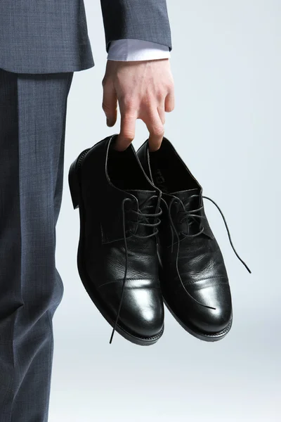 Hombre de negocios sosteniendo los zapatos en la mano, de cerca —  Fotos de Stock