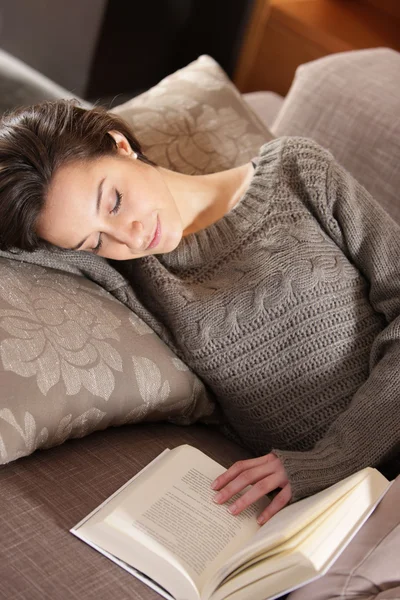 Wanita berbaring di sofa dengan buku — Stok Foto
