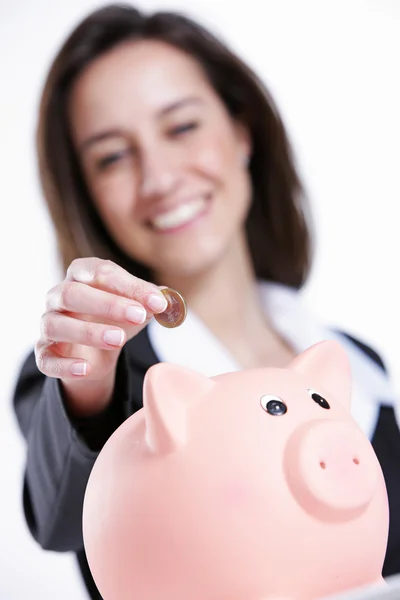 Close-up de jovem mulher colocando moeda em um banco porquinho — Fotografia de Stock