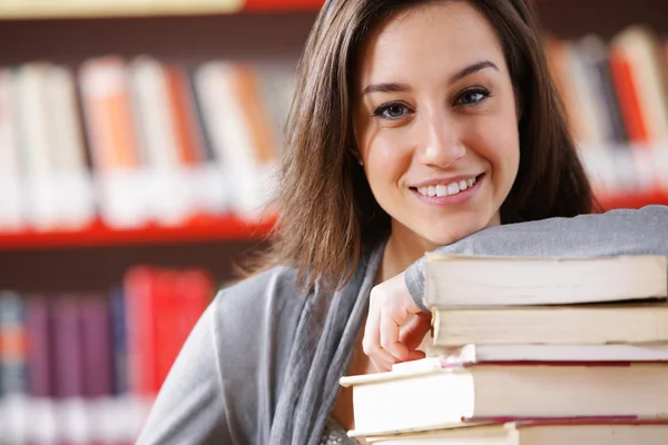 Studente universitario sorridente con una pila di libri — Foto Stock