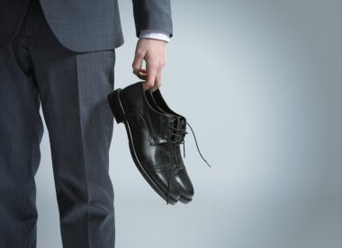 Businessman holding the shoes in hand, close up