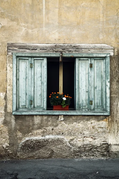 Gamla fönster med vas med röda blommor — Stockfoto