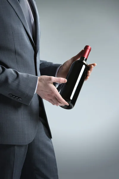 Zarif adam elinde bir şişe kırmızı şarap ile — Stok fotoğraf