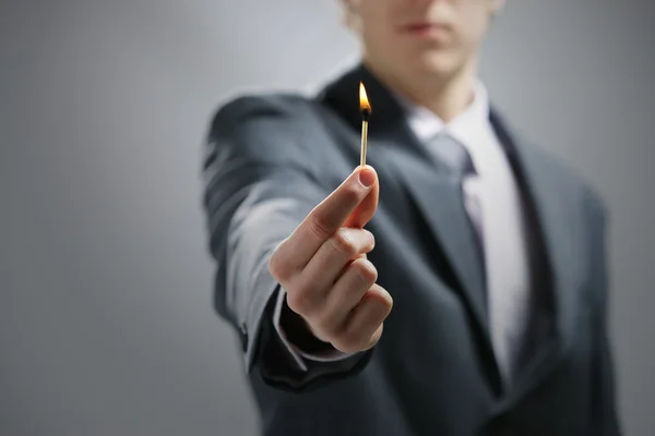 Geschäftsmann hält ein brennendes Streichholz in der Hand — Stockfoto