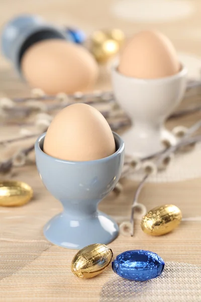 Ovos em copos de ovo brancos e azuis — Fotografia de Stock