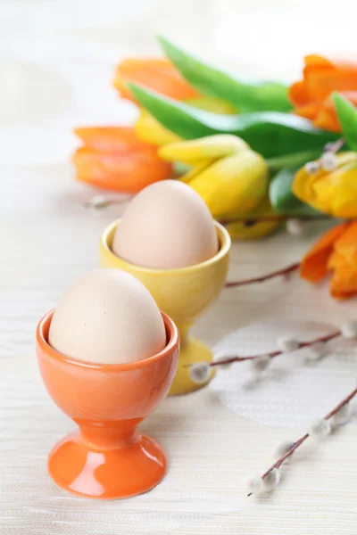 Ovos em copos de ovo laranja e amarelo — Fotografia de Stock
