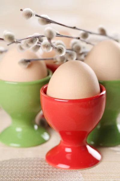 Ovos em copos de ovo vermelhos e verdes — Fotografia de Stock